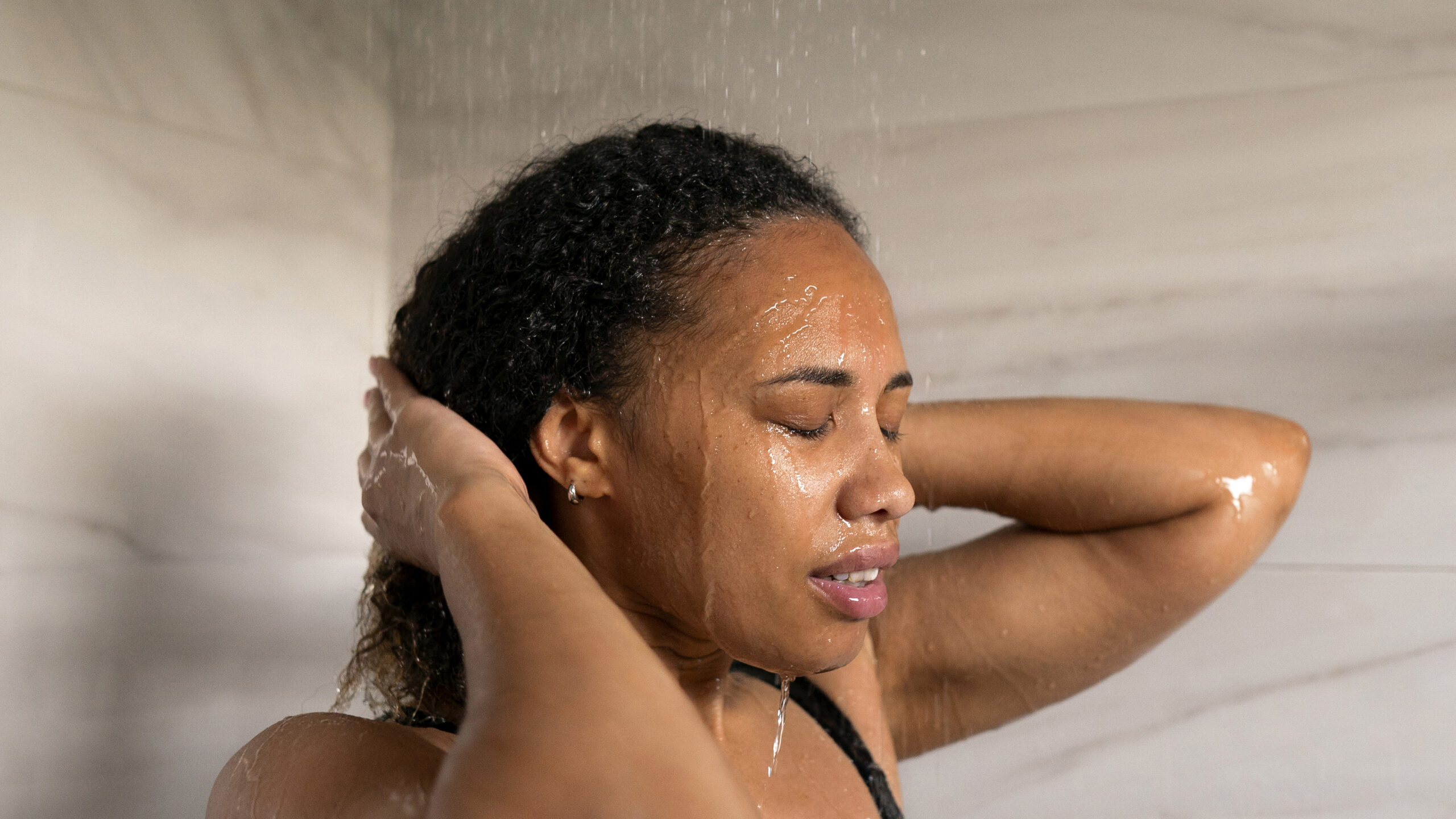 black woman taking shower with afro hair