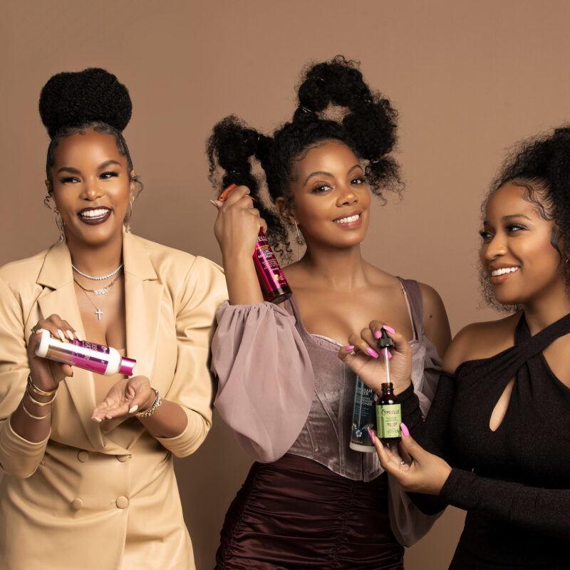 Three black women holding Mielle Organics products